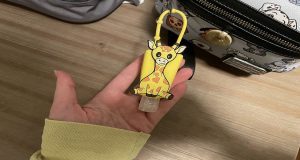 Giraffe hand sanitizer holder attached to a backpack